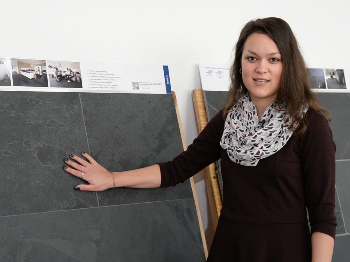 Pracownica stoi przed panelami z próbkami łupków