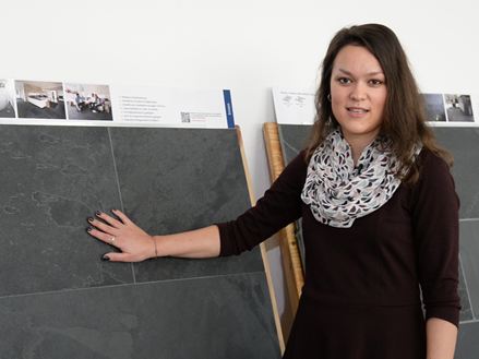 Pracownica stoi przed panelami z próbkami łupków