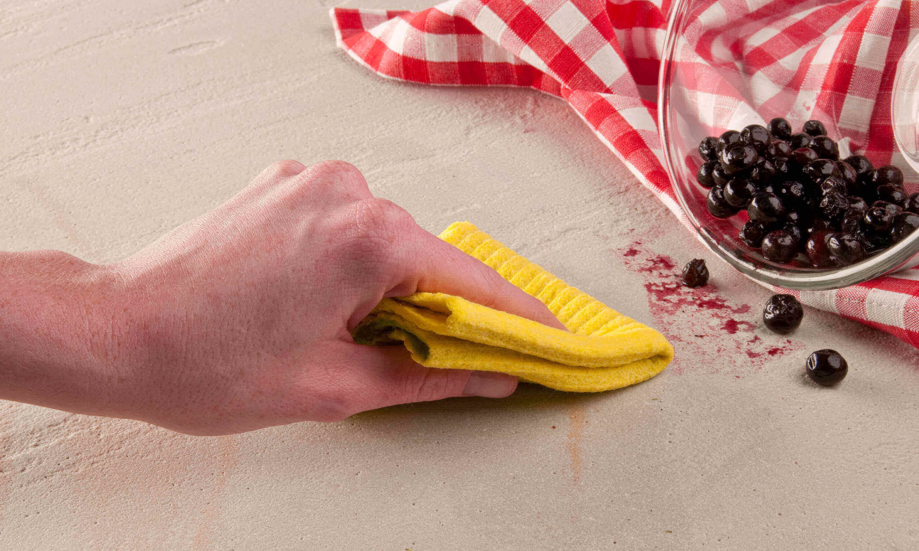 Ręka wyciera plamę z jagód żółtą chusteczką