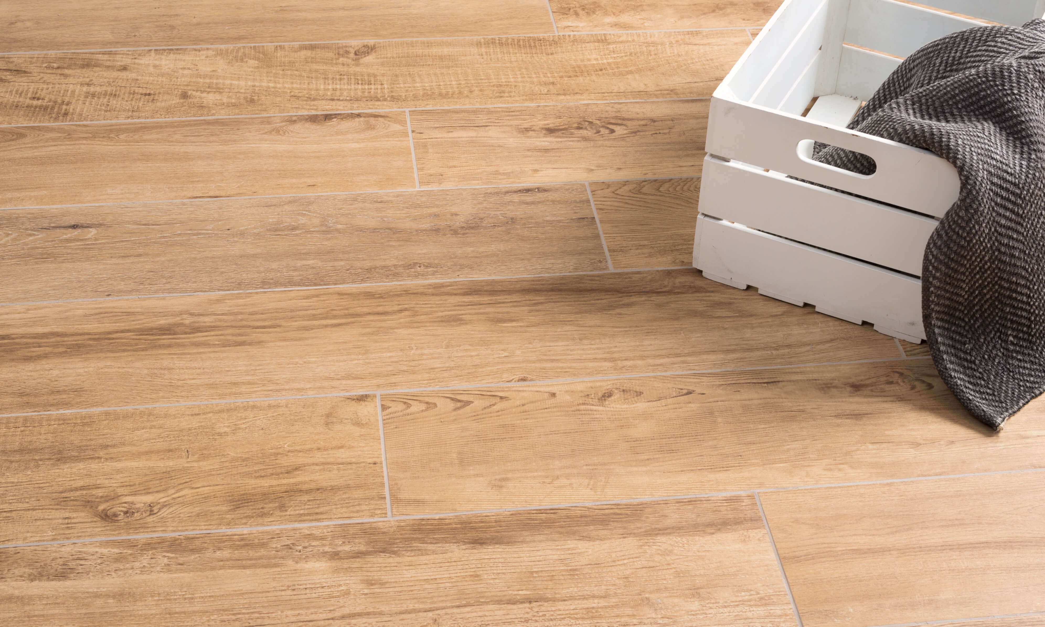 Białe pudełko na podłodze wyłożonej płytkami z gresu porcelanowego imitującymi drewno