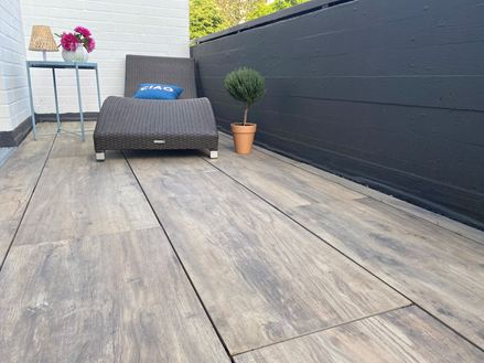 Balkon z leżakiem i płytami tarasowymi z gresu porcelanowego imitującego drewno jako pokrycie podłogowe