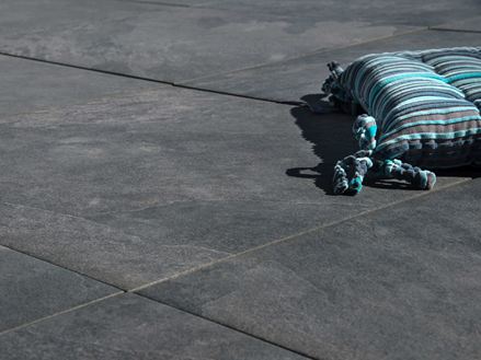 Poduszka leży na ciemnoszarych płytkach z gresu porcelanowego Alpine Black