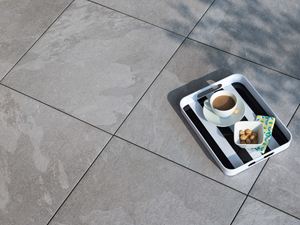 Taca z kawą na płytkach z gresu porcelanowego w jasnoszarym wzorze imitującym łupek „Alpine Grey”, sfotografowana z góry