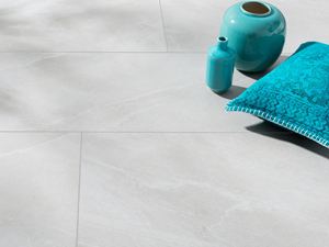 Płytki z gresu porcelanowego w jasnoszarym wzorze imitującym łupek z turkusowym wazonem i turkusową poduszką
