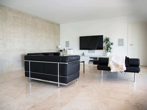 Nowoczesny salon z czarną sofą i jasnobeżowymi płytkami z trawertynu Classic Light jako wykładziną podłogową