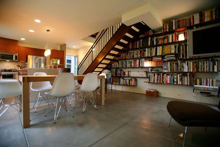 Nowoczesny salon z betonową podłogą i dużą regałową biblioteką w tle