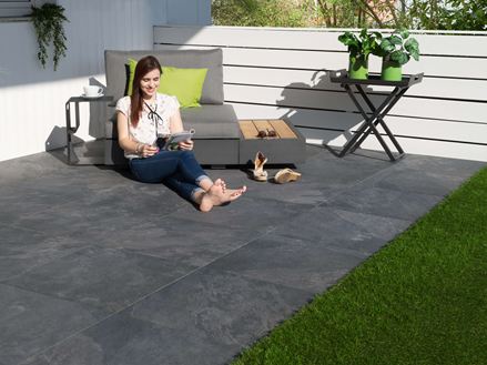 Kobieta siedzi na płytach tarasowych w kolorze Alpine Black